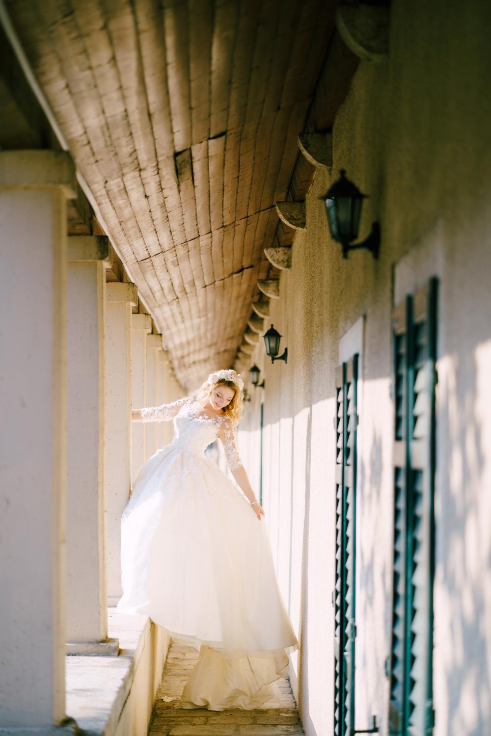 he bride stands on the balcony windowsill holding on to a column in an old house